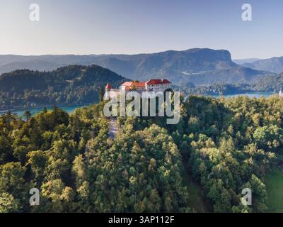 Luftaufnahme von Blejski Grad, einer schönen Burg auf einem Felsen mit Blick auf den Bleder See in der frühen Morgensonne, Oberkrain, Slowenien. Stockfoto