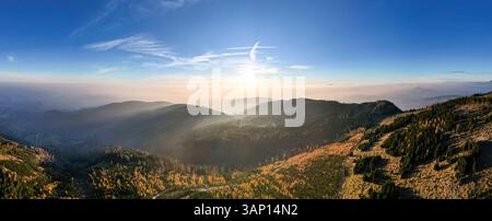 Aus der Vogelperspektive auf ein wunderschönes Panorama nebelbedeckter Berge bei Sonnenuntergang mit Herbstfarben, Schoeckl, Graz, Steiermark, Österreich. Stockfoto