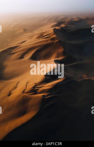 Aus der Vogelperspektive der riesigen orangen kurvigen Dünen in der Wüste, Dune 7, Walvis Bay, Namibia. Stockfoto