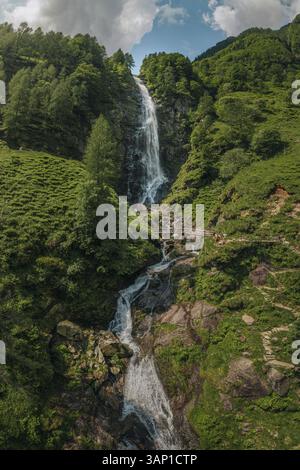 Drohnenblick auf den Wasserfall Cascata La Froda in Sonogno, umgeben von üppig grünen Gras und Bäumen, Verzasca, Schweiz. Stockfoto