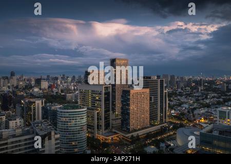 Blick aus der Vogelperspektive auf den Miyana-Turm und die Stadtlandschaft bei Sonnenuntergang mit wunderschönen Wolken, Miguel Hidalgo, Mexiko. Stockfoto