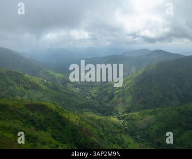 Aus der Vogelperspektive auf üppig grüne Berge und ein ruhiges Tal unter einem bewölkten Himmel, Obudu, Nigeria. Stockfoto