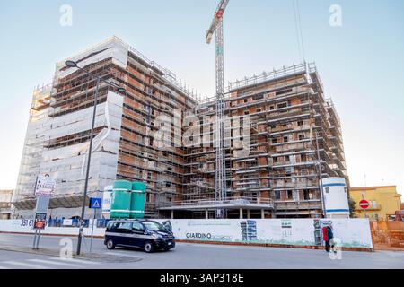 Sottomarina, Italien - 3. März 2025: Baustelle eines neuen Wohnkomplexes mit Gerüst und Kran während der Stadtsanierung Stockfoto