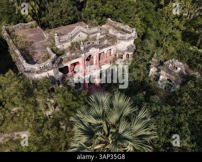 Blick aus der Vogelperspektive auf ein schönes denkmalgeschütztes Herrenhaus, umgeben von bewachsenem Grün und alten Ruinen, Narshingdi, Dhaka, Bangladesch. Stockfoto