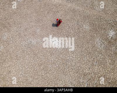 Aus der Vogelperspektive der zerrissenen Erde und einer Person, die Wasser sammelt, in einem von der Dürre betroffenen Küstendorf Khulna, Bangladesch. Stockfoto