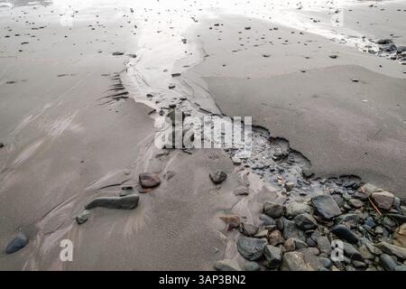 Malerischer Blick auf die Küste von Oregon mit glattem Sand und verstreuten Felsen. Stockfoto
