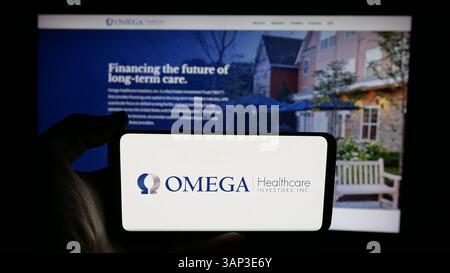 Stuttgart, Deutschland - 12.09.2024: Person, die ein Mobiltelefon mit dem Logo des US-amerikanischen Unternehmens Omega Healthcare Investors Inc. Auf dem Bildschirm hält Stockfoto