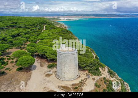 Aus der Vogelperspektive auf die Klippen entlang der Küste eines erhaltenen Gebiets mit türkisfarbenem Wasser und einem Wachturm aus dem 16. Jahrhundert, Torre del Tajo in der Provinz C. Stockfoto