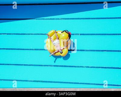 Aus der Vogelperspektive einer Person in einem Pool ohne Wasser, die auf einer riesigen Gummiente in einer Residenz in Moron de la Frontera, Sevilla, Spanien sitzt. Stockfoto