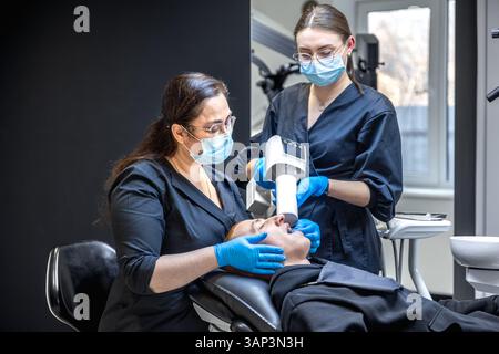 Ein Team von Zahnärzten behandelt die Zähne eines Patienten mit modernen Geräten. Zahnmedizinisches Konzept. Stockfoto