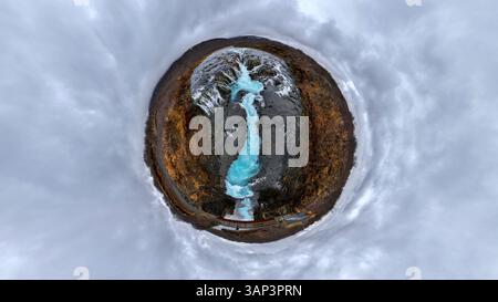 Aus der Vogelperspektive eines winzigen Planeten mit einem majestätischen Wasserfall, der in einen ruhigen Fluss unter einem dramatischen Wolkenhimmel stürzt, Selfoss, Southern Region, Stockfoto