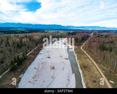 Aus der Vogelperspektive auf die klare Emme, die durch bewaldete Berge unter einem ruhigen Himmel fließt, Utzenstorf, Schweiz. Stockfoto
