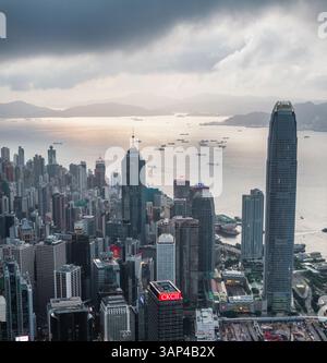 Blick aus der Vogelperspektive auf die wunderschöne Skyline mit modernen Wolkenkratzern und den Hafen voller Schiffe unter einem bewölkten Himmel, Wan Chai, Hongkong. Stockfoto
