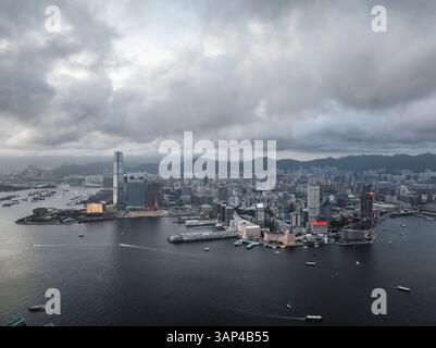 Blick aus der Vogelperspektive auf eine pulsierende Stadtlandschaft mit Wolkenkratzern und einem geschäftigen Hafen bei Sonnenuntergang, Central and Western, Hongkong. Stockfoto