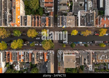 Blick aus der Vogelperspektive auf den Amsterdamer Kanal von oben, Blick auf mehrere Boote, die entlang des Flusses in der Innenstadt von Amsterdam, Niederlande, ankern. Stockfoto