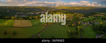 Blick aus der Vogelperspektive auf das ruhige ländliche Dorf, umgeben von üppigen Feldern und sanften Hügeln, Chenailler-Mascheix, Frankreich. Stockfoto