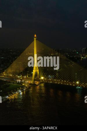 Aus der Vogelperspektive auf die Rama VIII Brücke, eine Kabelbrücke über den Chao Phraya Fluss bei Nacht in Bangkok, Thailand. Stockfoto