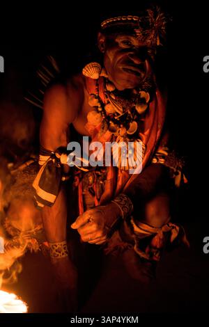 Porträt eines Mannes am heiligen Feuer, gekleidet in einem rituellen Kostüm während einer Bwiti-Zeremonie. Stockfoto