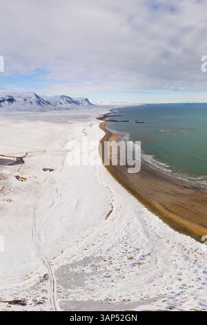 Aus der Vogelperspektive auf die Küste entlang des mit Schnee bedeckten Landes, Snaefellsnes, Island. Stockfoto