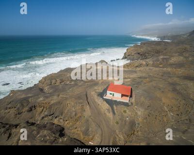 Aus der Vogelperspektive eines kleinen Hauses an der felsigen Vulkanküste von La Pared, Fuerteventura, Kanarischen Inseln. Stockfoto