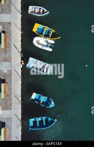 Von oben nach unten sehen Sie farbenfrohe, winzige Boote, die entlang des Piers, Marsaxlokk, Malta, schwimmen. Stockfoto