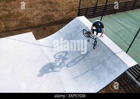 Luftaufnahme eines BMX-Radfahrers, der auf der Rampe im Skatepark Panevezys, Litauen, springt und trickt. Stockfoto