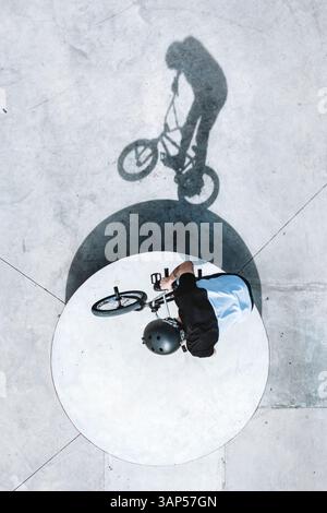 Luftaufnahme des Silhouettenschattens des BMX-Fahrradfahrers beim Sprung auf Betonelement im Skatepark in Panevezys, Litauen. Stockfoto