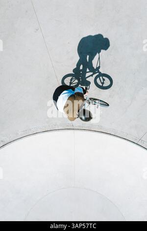 Von oben nach unten auf die Silhouette des BMX-Fahrradfahrers im Betonskate-Pool in der Nähe von Panevezys, Litauen. Stockfoto