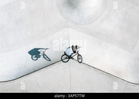 Aus der Vogelperspektive eines BMX-Radfahrers, der einen Sprung und einen Trick mit einer Bar im örtlichen Skatepark in der Nähe von Panevezys, Litauen, macht. Stockfoto