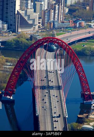 Aus der Vogelperspektive auf die wunderschöne Stadtlandschaft mit einer roten Brücke über einen Fluss mit hohen Gebäuden und Verkehr, Moskau, Russland. Stockfoto