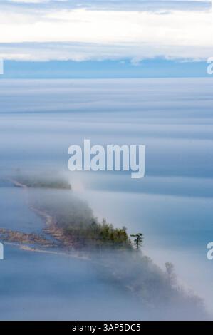 Blick aus der Vogelperspektive auf den ruhigen Baikalsee, umgeben von Nebel und Bäumen, südsibirisches Russland. Stockfoto