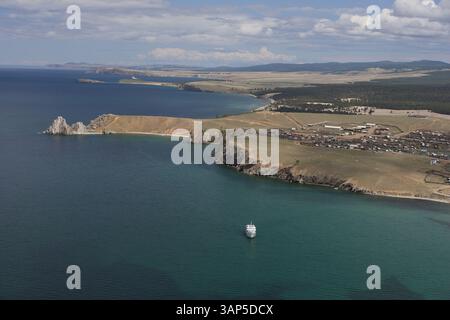 Blick aus der Vogelperspektive auf den ruhigen Baikalsee mit einem ruhigen Dorf und Klippen, Khuzhir, Russland. Stockfoto
