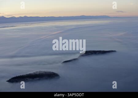 Aus der Vogelperspektive auf den ruhigen Baikalsee mit Nebel und nebeligen Bergen, Oblast Irkutsk, Russland. Stockfoto