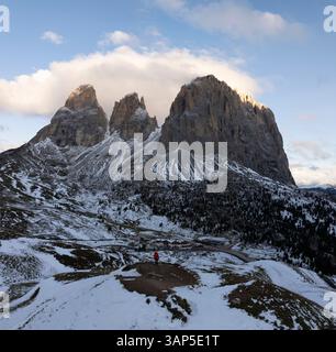 Aus der Vogelperspektive auf majestätische schneebedeckte Gipfel und zerklüftete Felsformationen inmitten heiterer Wolken, Canazei, Italien. Stockfoto