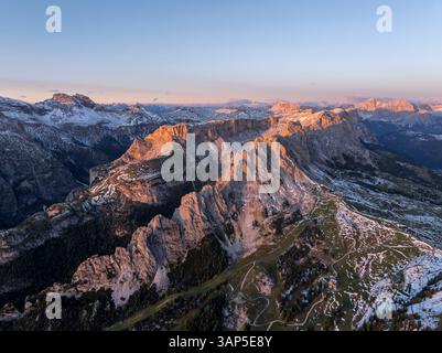 Aus der Vogelperspektive auf die majestätischen dolomiten mit schneebedeckten Gipfeln und einem ruhigen Tal bei Sonnenuntergang, Wolkenstein, Italien. Stockfoto
