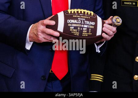 Washington, Usa. April 2025. Präsident Donald Trump hält einen Fußball- und Meisterschaftsring im Rahmen einer Veranstaltung, bei der er den Navy Midshipmen der United States Naval Academy die Commander-in-Chief Trophy nach ihrem Meisterschaftssieg im East Room des Weißen Hauses in Washington DC am Dienstag, den 15. April 2025, überreichte. (Foto: Aaron Schwartz/SIPA USA) Credit: SIPA USA/Alamy Live News Stockfoto