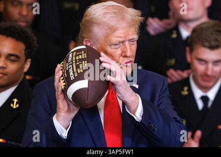 Washington, Usa. April 2025. Präsident Donald Trump hält während einer Veranstaltung, bei der er den Navy Midshipmen der United States Naval Academy die Commander-in-Chief Trophy nach ihrem Meisterschaftssieg im East Room des Weißen Hauses in Washington DC am Dienstag, den 15. April 2025, überreichte. (Foto: Aaron Schwartz/SIPA USA) Credit: SIPA USA/Alamy Live News Stockfoto
