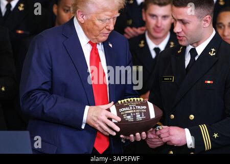 Washington, Usa. April 2025. Präsident Donald Trump hält einen Fußball- und Meisterschaftsring im Rahmen einer Veranstaltung, bei der er den Navy Midshipmen der United States Naval Academy die Commander-in-Chief Trophy nach ihrem Meisterschaftssieg im East Room des Weißen Hauses in Washington DC am Dienstag, den 15. April 2025, überreichte. (Foto: Aaron Schwartz/SIPA USA) Credit: SIPA USA/Alamy Live News Stockfoto