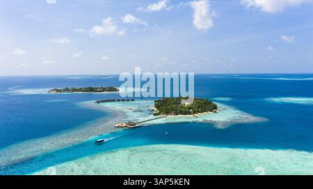 Blick aus der Vogelperspektive auf ein luxuriöses Resort mit Villen über dem Wasser und die lokale Insel Mathiveri im Hintergrund, Malediven, Laccadive Meer. Stockfoto