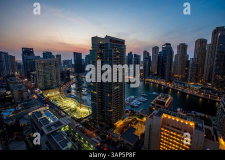 Dubai, Vereinigte Arabische Emirate - 23. Oktober 2018: Aus der Vogelperspektive beleuchtete Wolkenkratzer und Yachthafen mit bunten Booten, die sich im Wasser spiegeln, Dubai, U Stockfoto