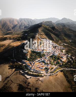 Aus der Vogelperspektive von Zahara de la Sierra, einer kleinen Stadt auf einem Hügel mit Bergen im Hintergrund, Spanien. Stockfoto
