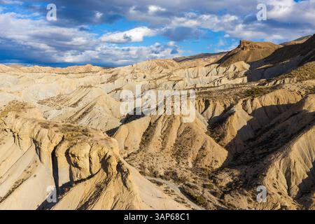 Aus der Vogelperspektive auf die Wüste Tabernas mit zerklüfteten Felsformationen und Hügeln unter einem bewölkten Himmel, Tabernas, Provincia de Almeria, Spanien. Stockfoto