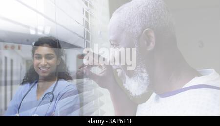 Komposit aus lächelndem älteren Mann, der aus dem Fenster blickt, und lächelnder Ärztin im Krankenhaus Stockfoto