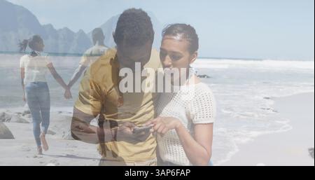 Zusammengesetzt aus glücklichen afroamerikanischen Paaren, die ein Smartphone verwenden und Hände am Strand halten Stockfoto
