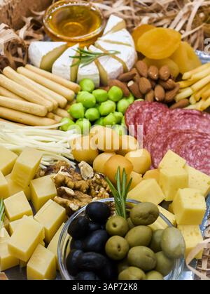 Gourmetgerichte mit einer Auswahl an Käse, Aufschnitt, Oliven und Früchten, perfekt für eine Feier oder gemütliche Zusammenkunft Stockfoto