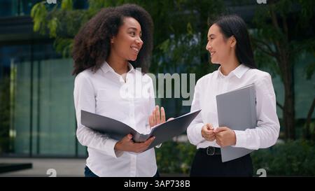 Afroamerikanerin hält Ordner Dokumentenpapiere Show Asiatische Koreanische Frauen sprechen über Geschäftsprojektplan Team Vertrag weibliche Geschäftsfrauen Stockfoto