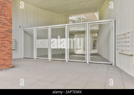 Ein zeitgenössischer Eingang mit Mesh-Türdesign, schlanken Linien und minimalistischer Ästhetik, ergänzt durch ein industrielles Ambiente. Stockfoto