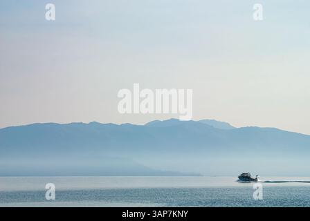 Ein Schnellboot rastet am späten Nachmittag bei trübem Licht über die ruhige Oberfläche des Lake Tahoe, vom Ufer des Ed Zberg State Park im Placer County, Kalifornien Stockfoto