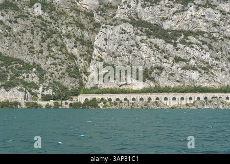 Blick über den Gardasee bis zur Seestraße, Gardesana Occidentale in der Nähe des beliebten Ferienorts Limone Sul Garda in Italien Stockfoto