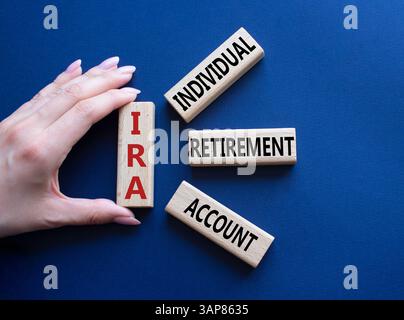 IRA - Symbol für individuelles Abgangskonto. Konzeptwort IRA auf Holzblöcken. Geschäftsmann Hand. Wunderschöner tiefblauer Hintergrund. Business und IRA Konz Stockfoto
